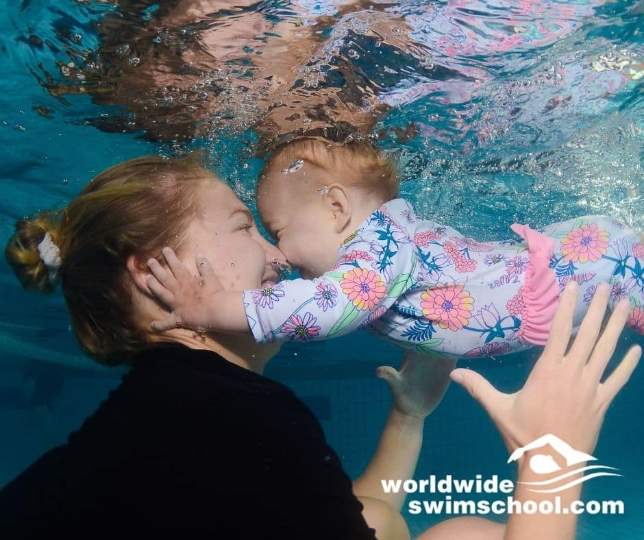 mother and baby daughter underwater in swimming pool happy smiling