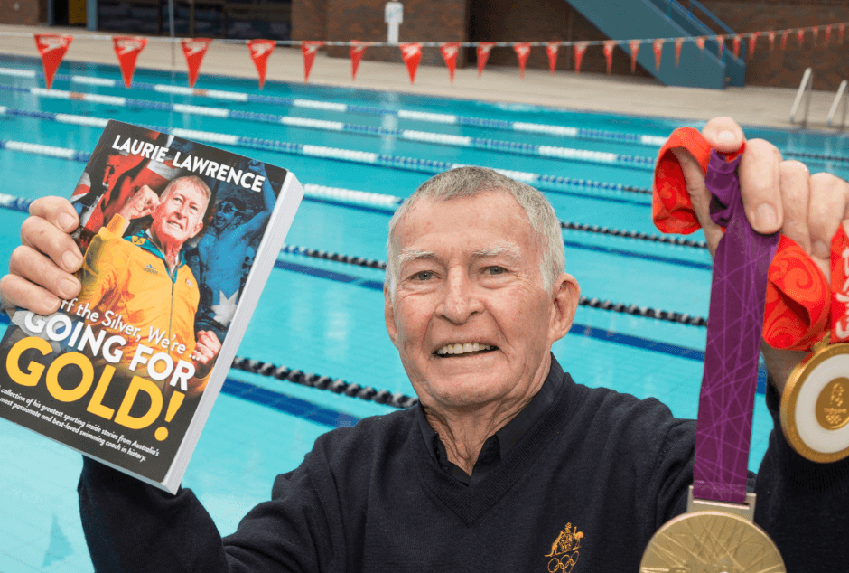 Laurie Lawrence holding new book with gold medals