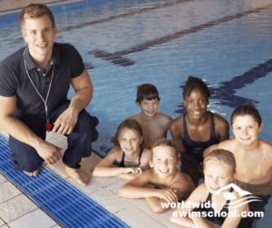 male swim coach on side of pool with group of swimmers