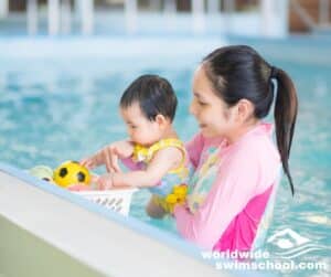 mother holding baby in pool baby playing in swimming pool with toys