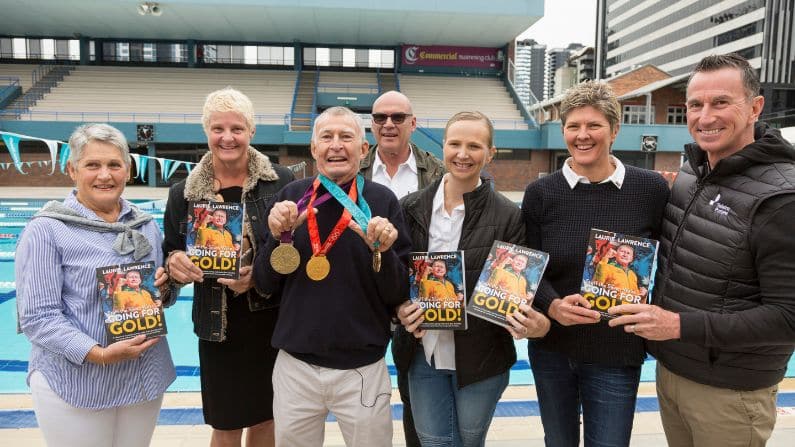 Laurie with swimmers he coached at book launch stuff the silver go for gold
