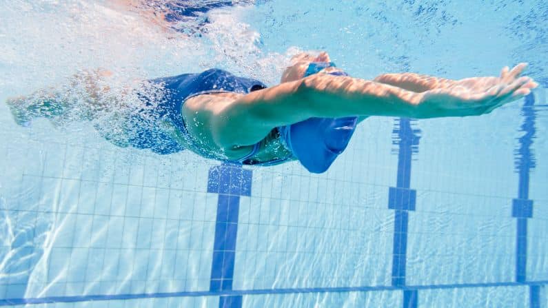 swimmer demonstrating backstroke push off from wall underwater