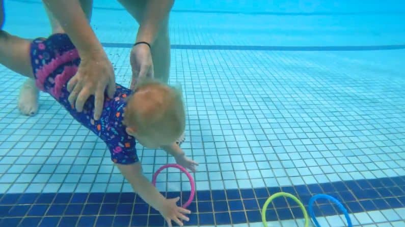 baby diving for rings underwater