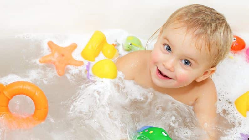 baby happy playing in bath with toys