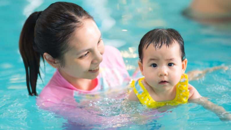 baby swimming in pool water with mother