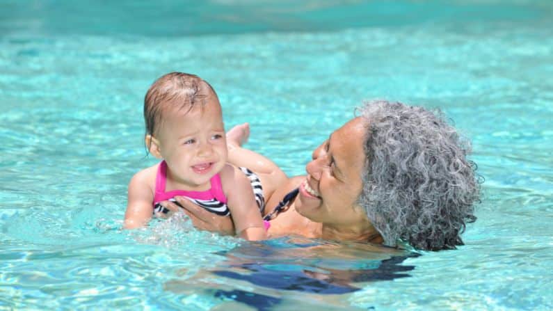 baby swimming in swimming pool with parent