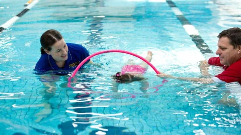 baby swimming underneath hoop in pool underwater