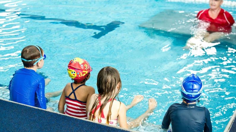 children looking at swim teacher in swimming pool