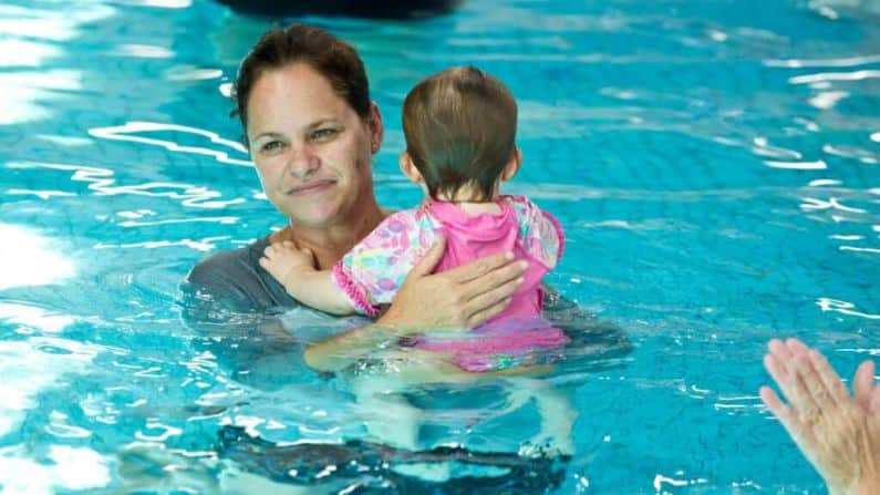 mother cuddle baby girl in swimming pool