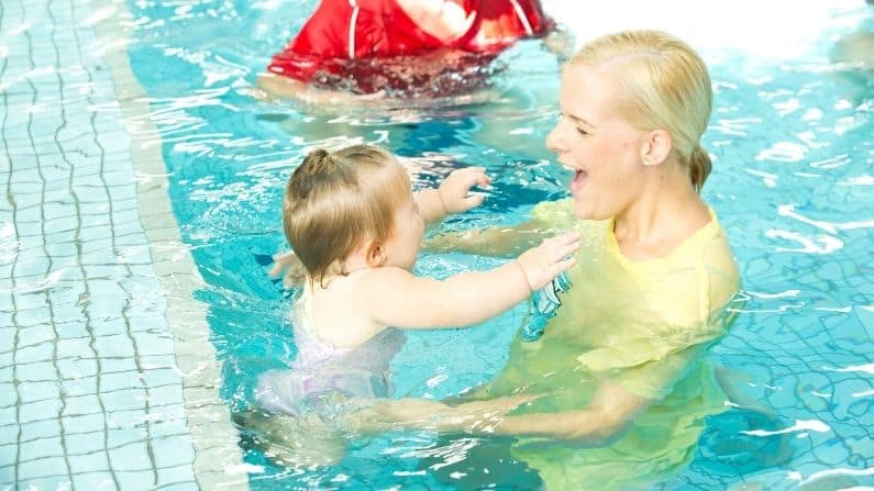 mother with baby daughter in swimming pool happy