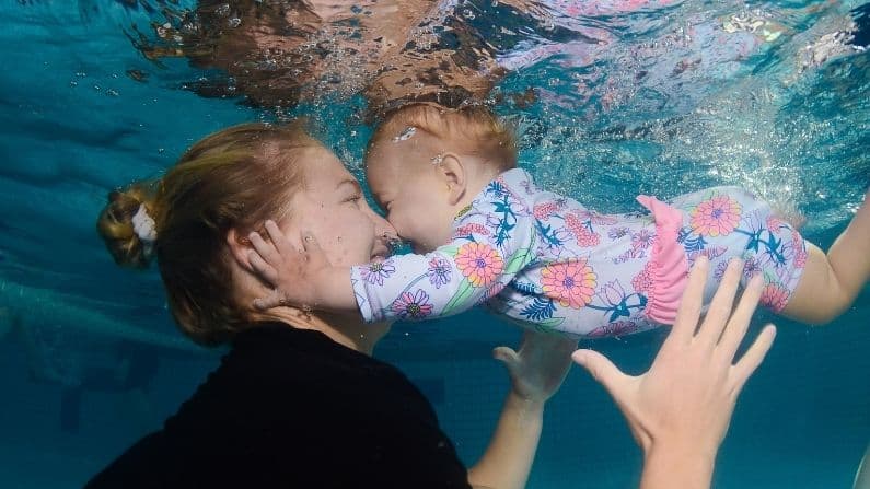 mother with baby daughter in swimming pool underwater