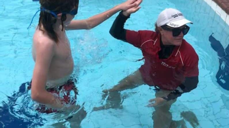 swimmer with coach in swimming pool high five