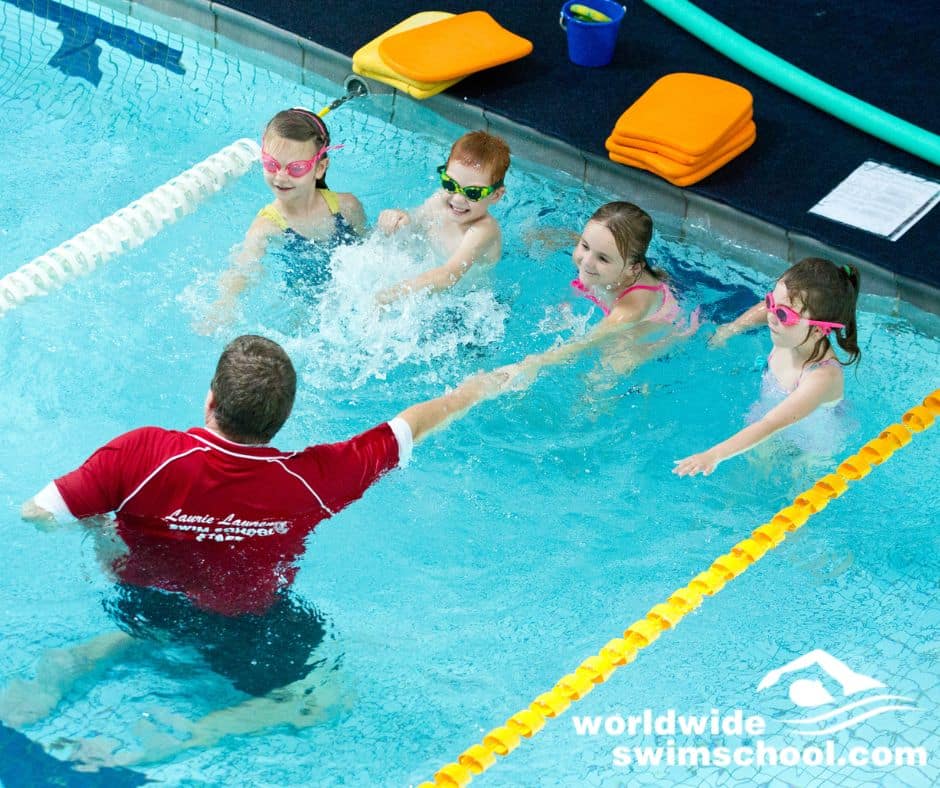 swim teacher teaching children freestyle in swimming pool